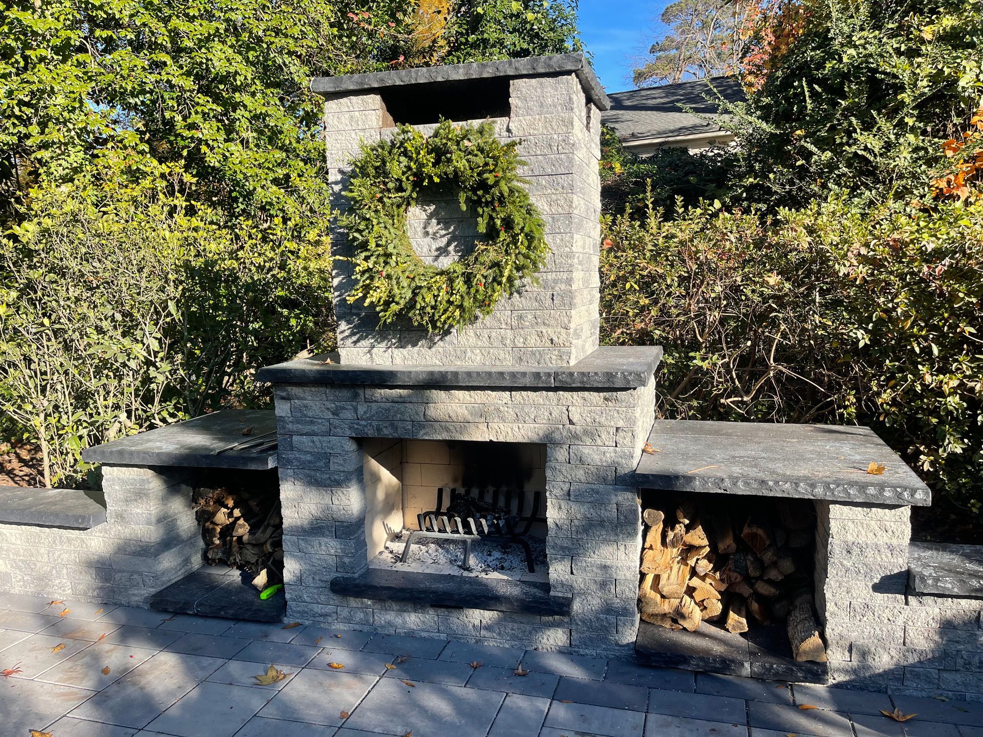 Outdoor stone fireplace with wood storage and a wreath.