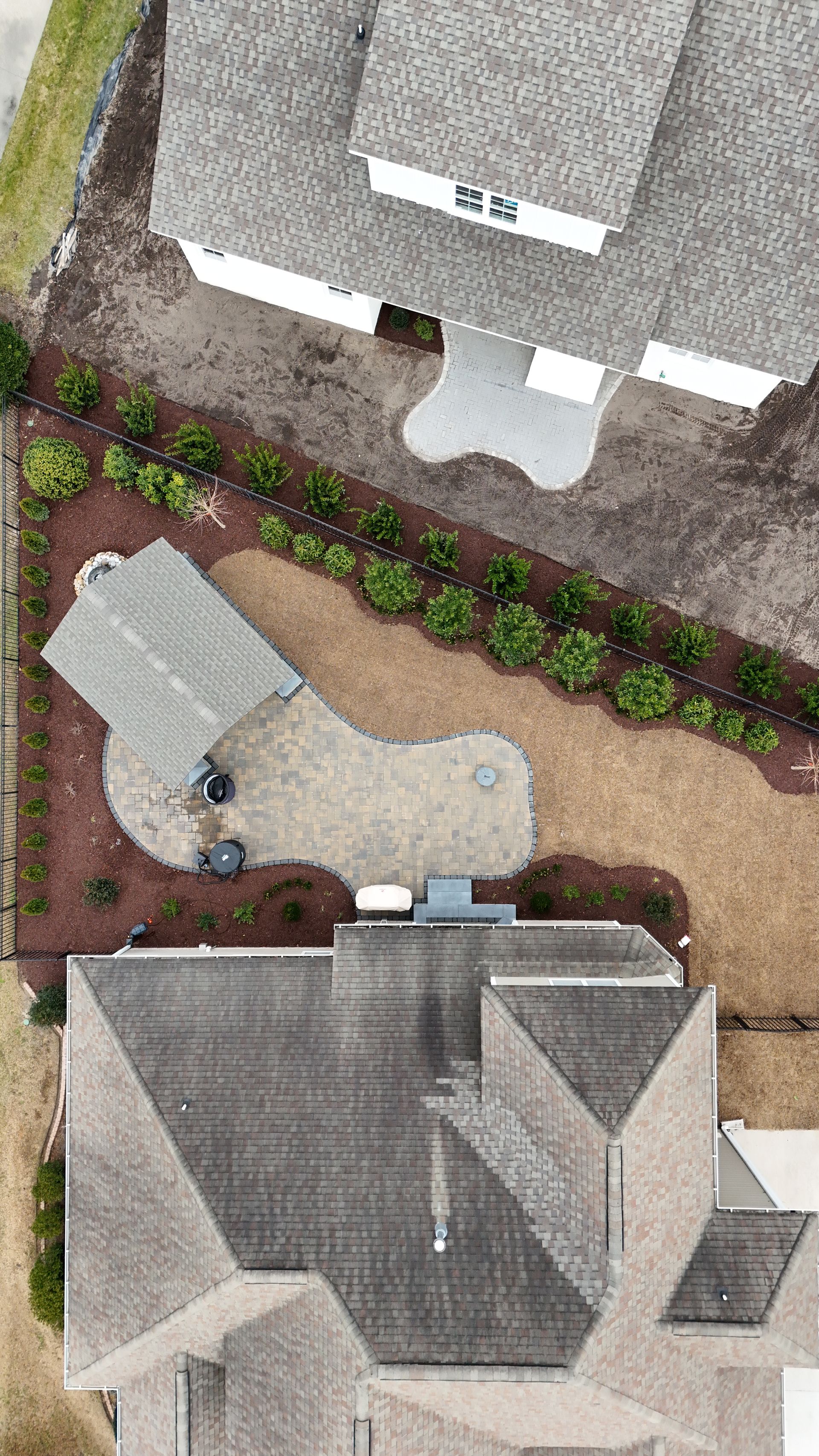 Overhead view of homes, landscaped yard with patio, and covered seating area.