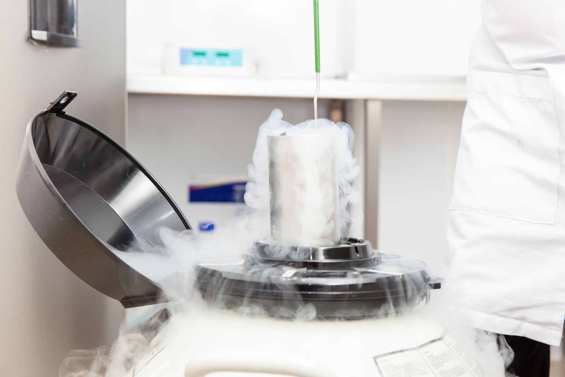 Liquid nitrogen being poured into a cryogenic storage tank, producing vapor in a lab.