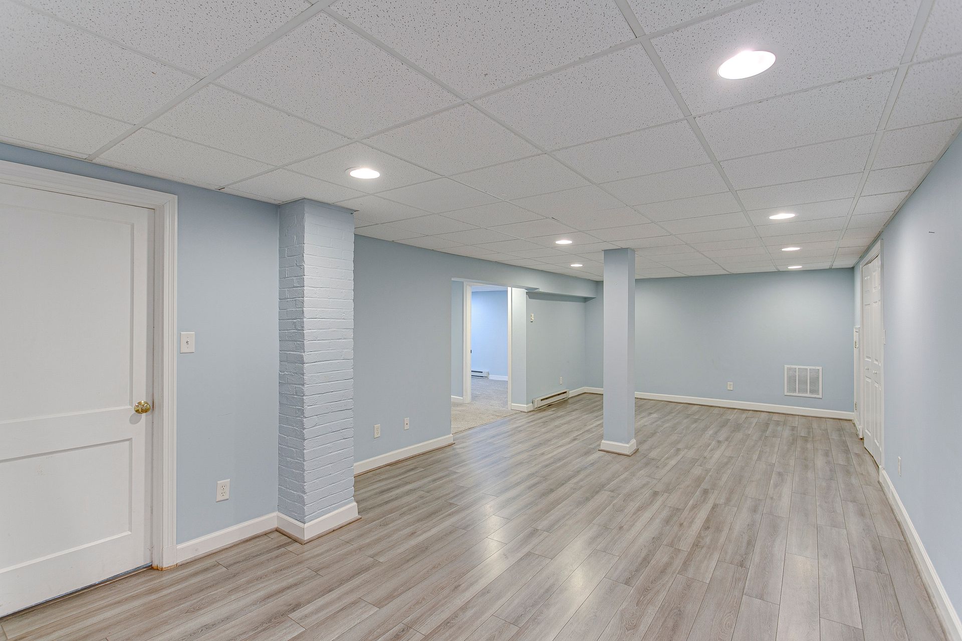 Finished basement with light blue walls, white doors, and gray flooring.