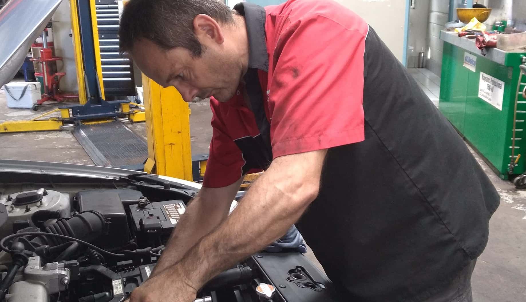 A Man Is Working On The Engine Of A Car In A Garage — Headland Auto Servicing & Air Conditioning In Alexandra Headland, QLD
