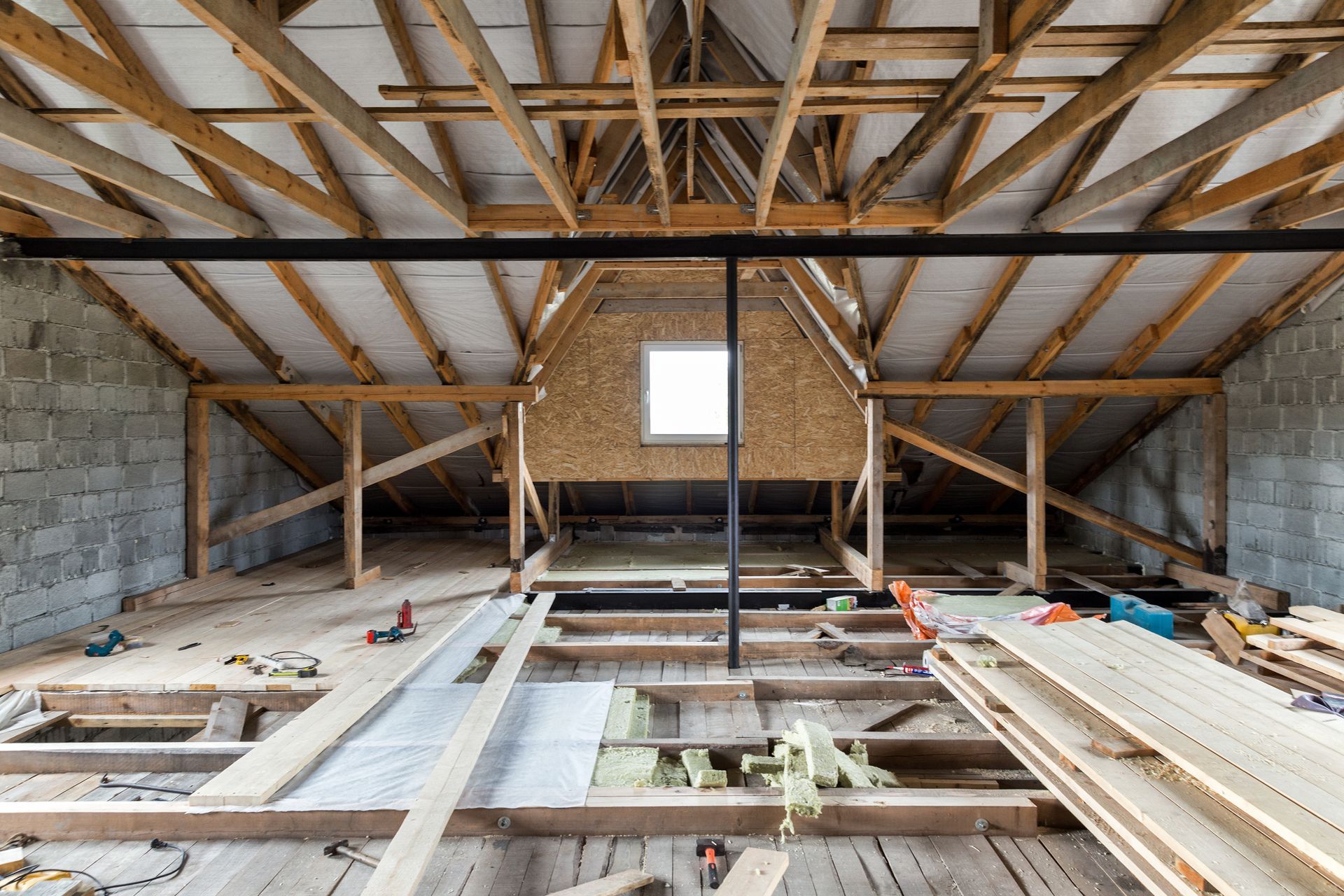 Intérieur d'un grenier en bois en construction, avec poutres apparentes et plancher non fini.