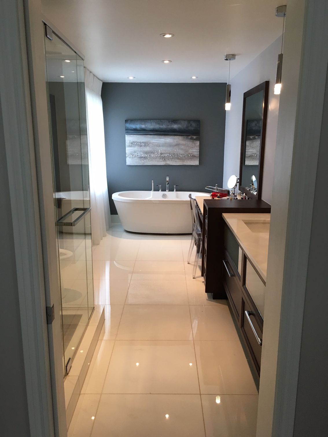 Modern bathroom with white tile floor, bathtub, and blue accent wall.