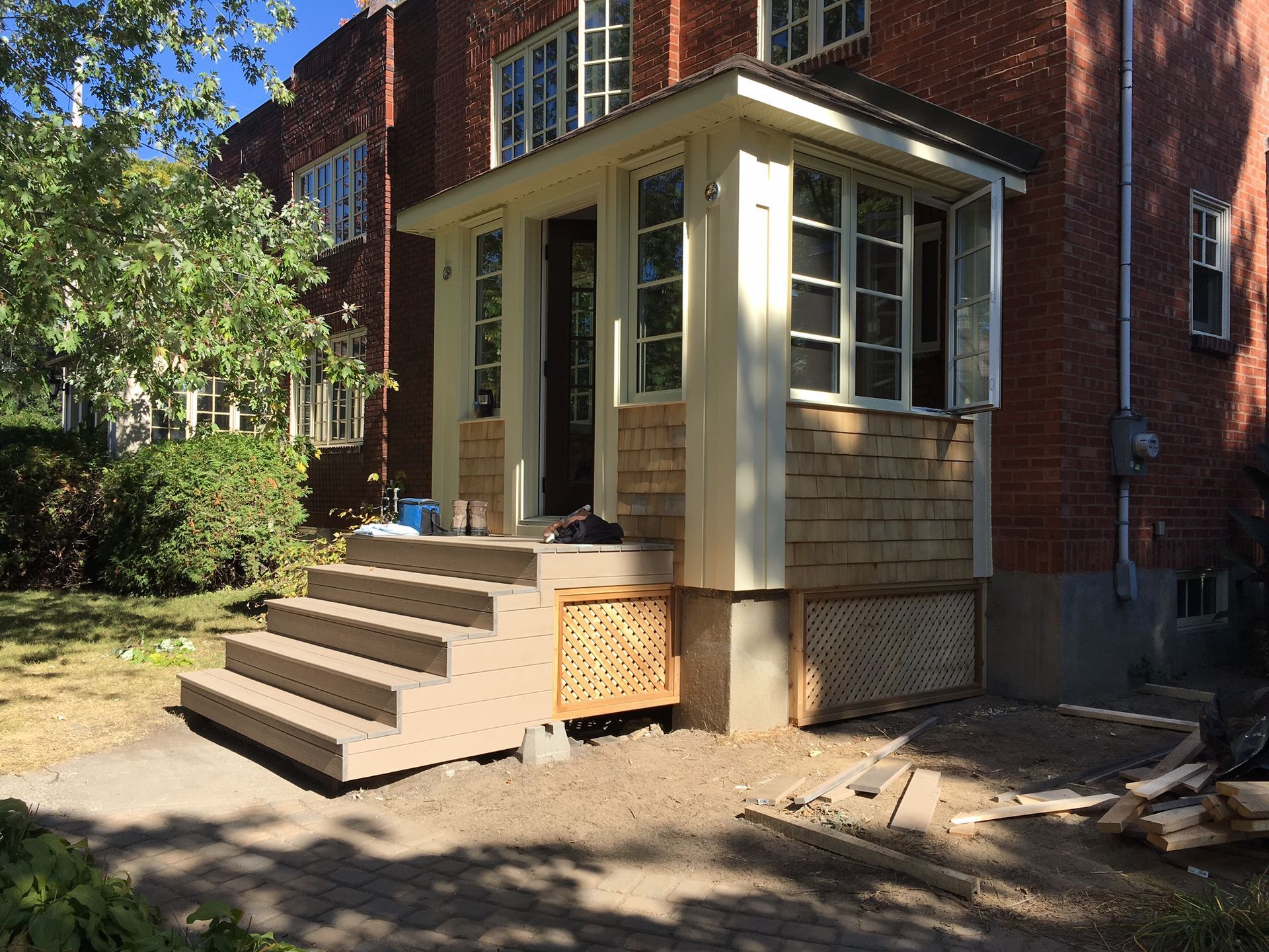 Exterior view of a brick house with a front porch, concrete steps, and wooden accents.
