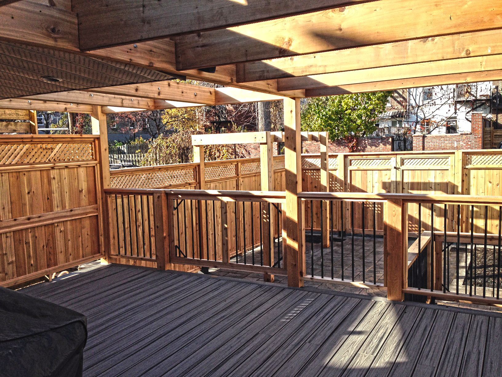 Wooden deck with railings and fencing; view of a backyard.