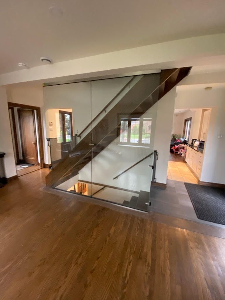Modern staircase with glass panels and wooden steps in a home.