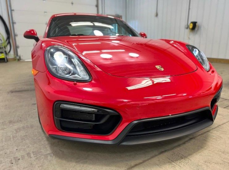 Red sports car in a garage, front view with glossy finish and headlights visible