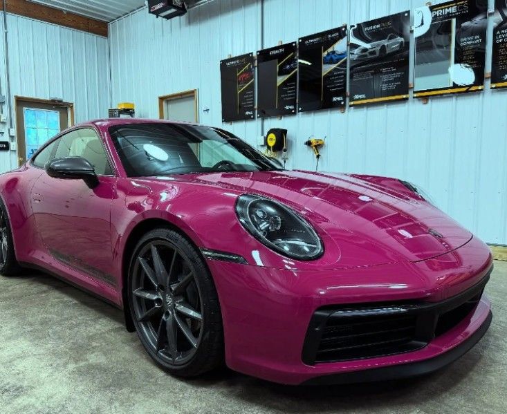 Bright pink sports car parked in a garage with posters on the wall