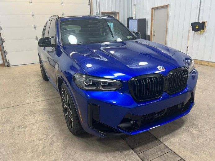 Blue BMW SUV parked indoors in a garage, front three-quarter view.