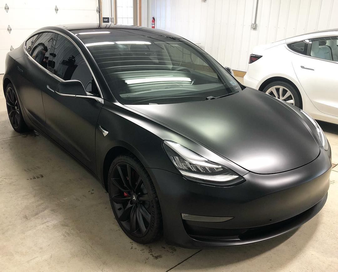 Black matte Tesla car parked indoors.