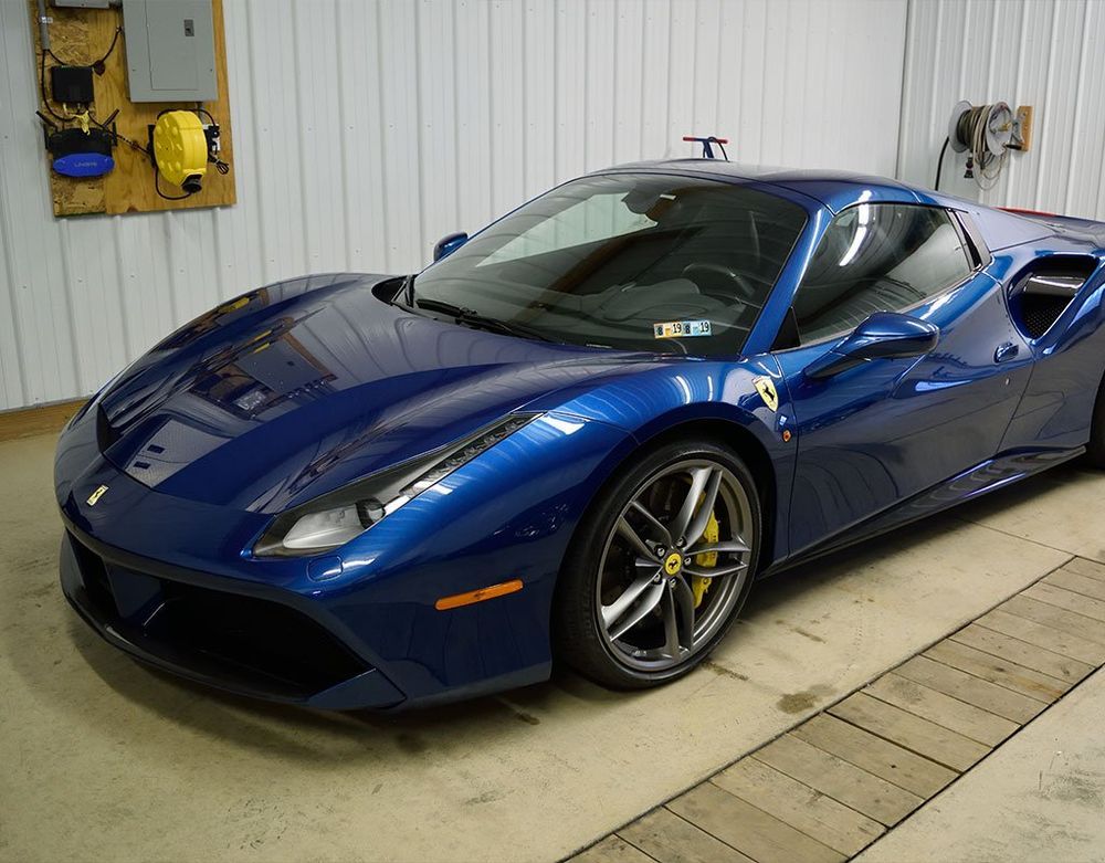 Blue Ferrari sports car parked inside a garage.