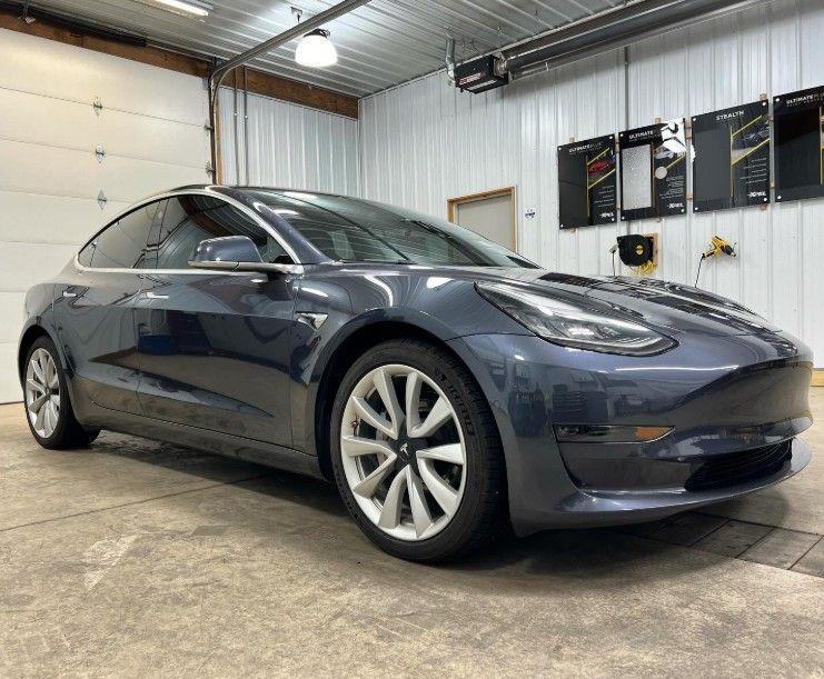 Dark blue Tesla sedan parked inside a garage workshop