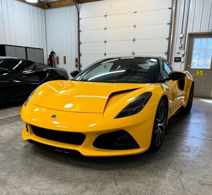 Yellow sports car parked indoors in a garage, front view with black accents