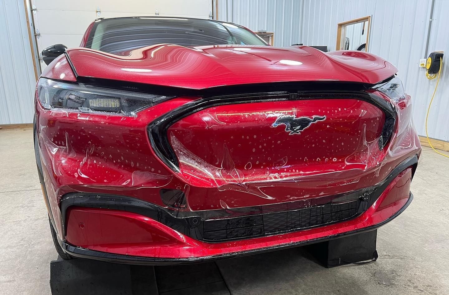A red ford mustang is sitting on blocks in a garage.