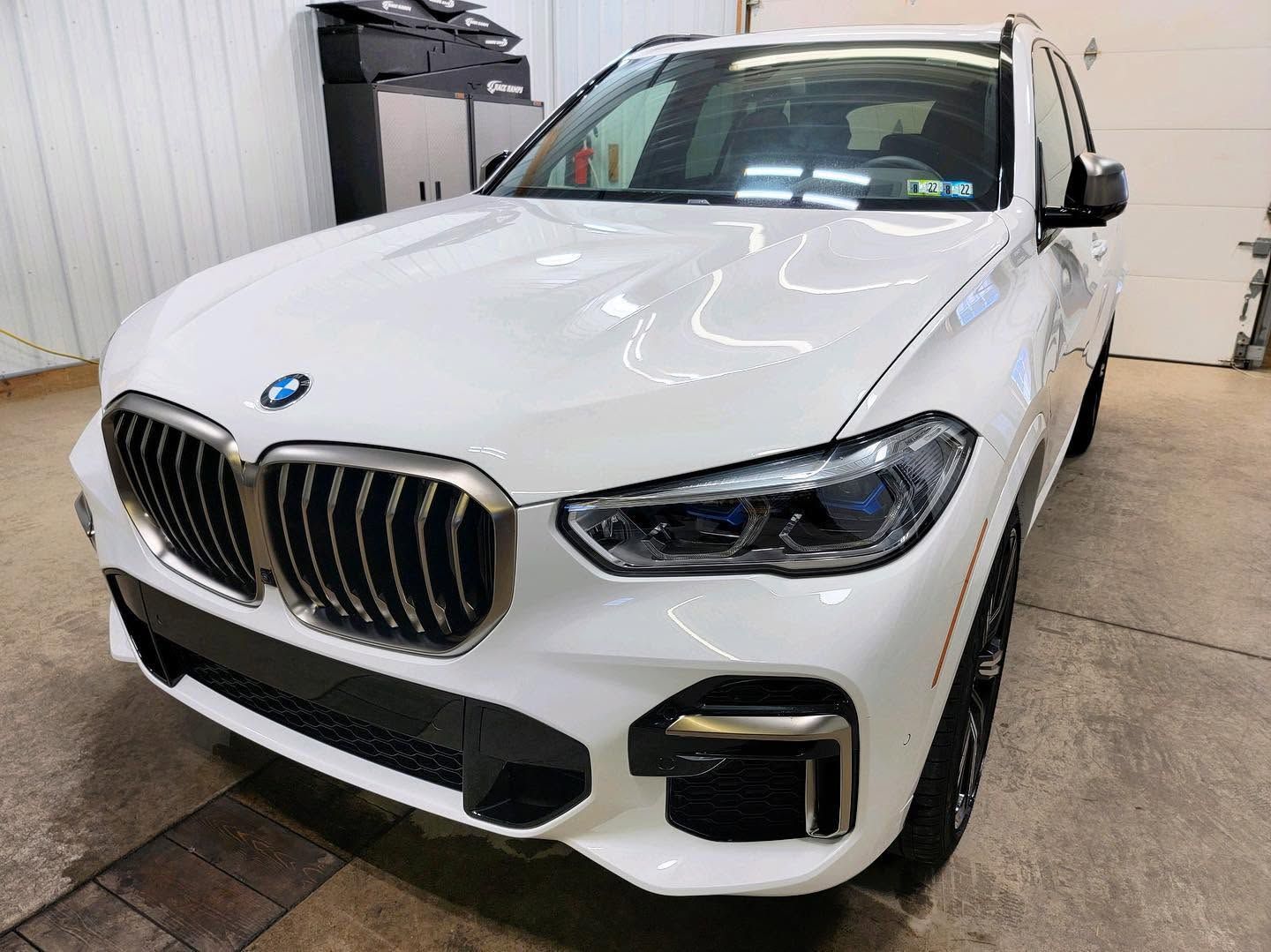 Silver BMW sedan parked indoors in a garage, front-left view.