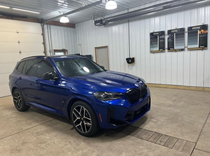 Blue BMW SUV parked in a garage with white metal walls and concrete floor