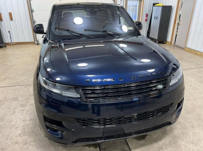 Front view of a dark blue Rivian SUV parked indoors in a garage