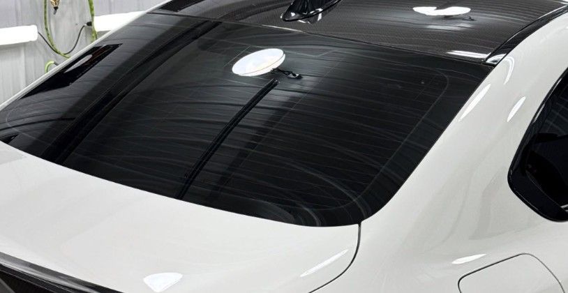 White car with tinted rear window, inside a workshop.
