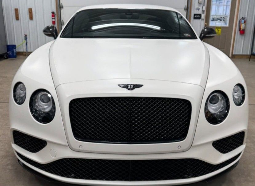 White Bentley coupe, front view, black grille and accents, in a garage.