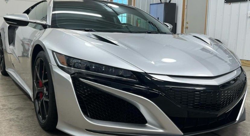 Silver Acura NSX sports car, front view. Black grille, red brake calipers.