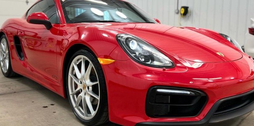 Red Porsche sports car parked inside a garage.