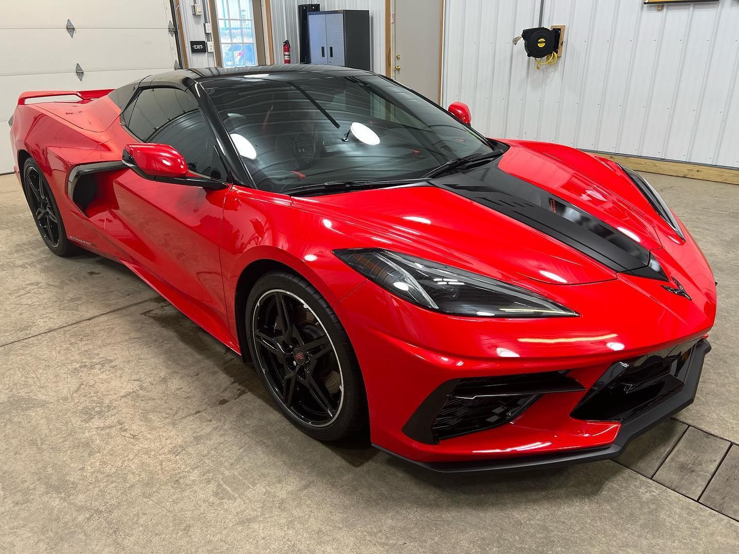 Red sports car parked indoors in a garage, front three-quarter view.