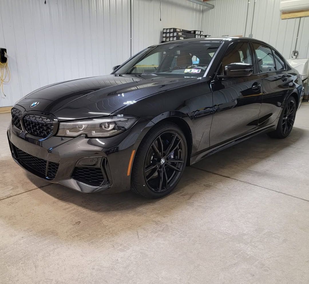 Black BMW sedan parked indoors in a garage, front-left view