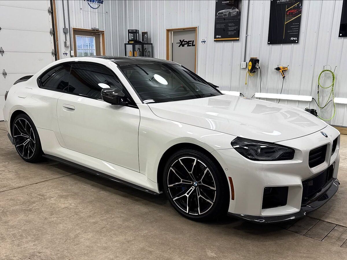 White sports sedan with black wheels parked inside a garage