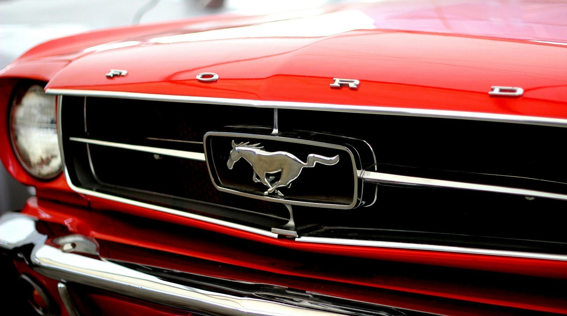 Red Ford Mustang front end with chrome grill and running horse emblem.