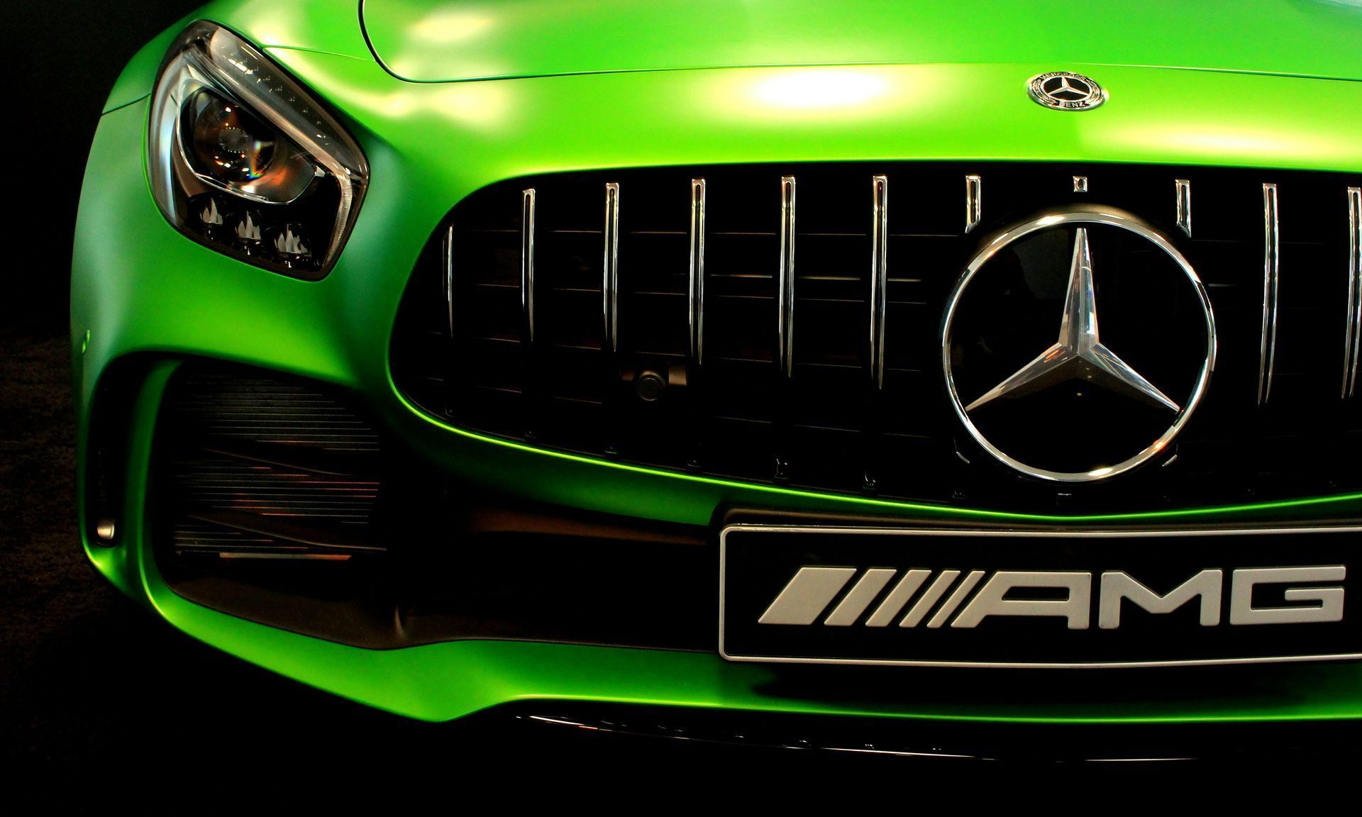 Green Mercedes-AMG sports car front view with the logo prominently displayed on the grill.