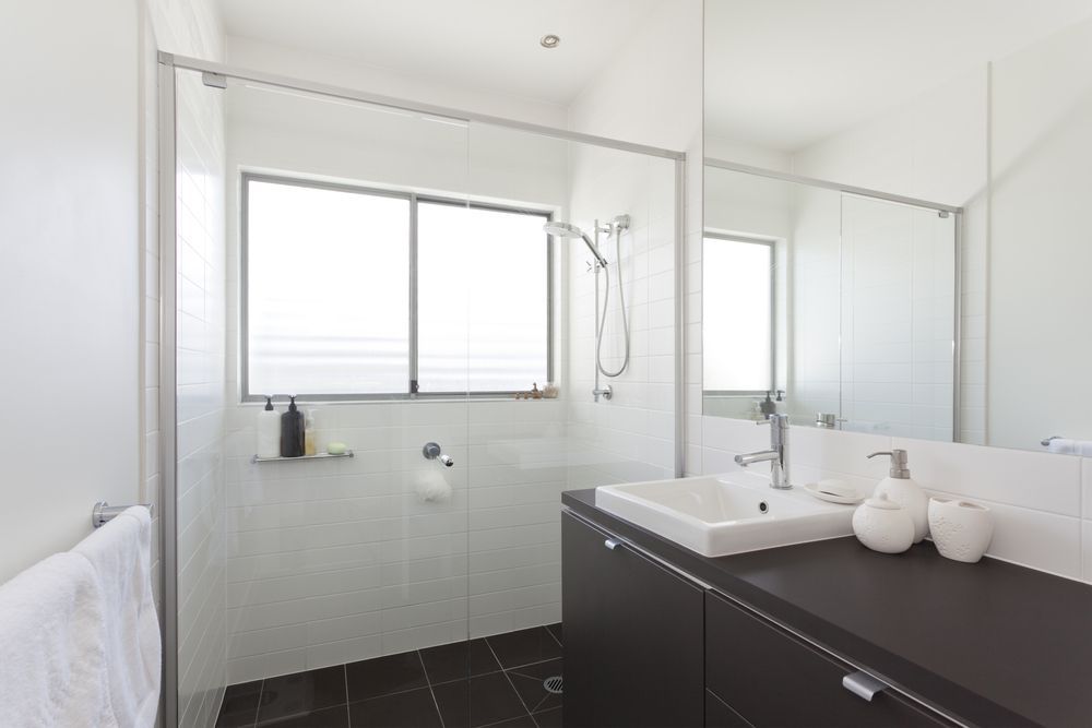 A Bathroom With a Sink, Mirror, Shower and Window — Leemark Design Services In Redlynch, QLD