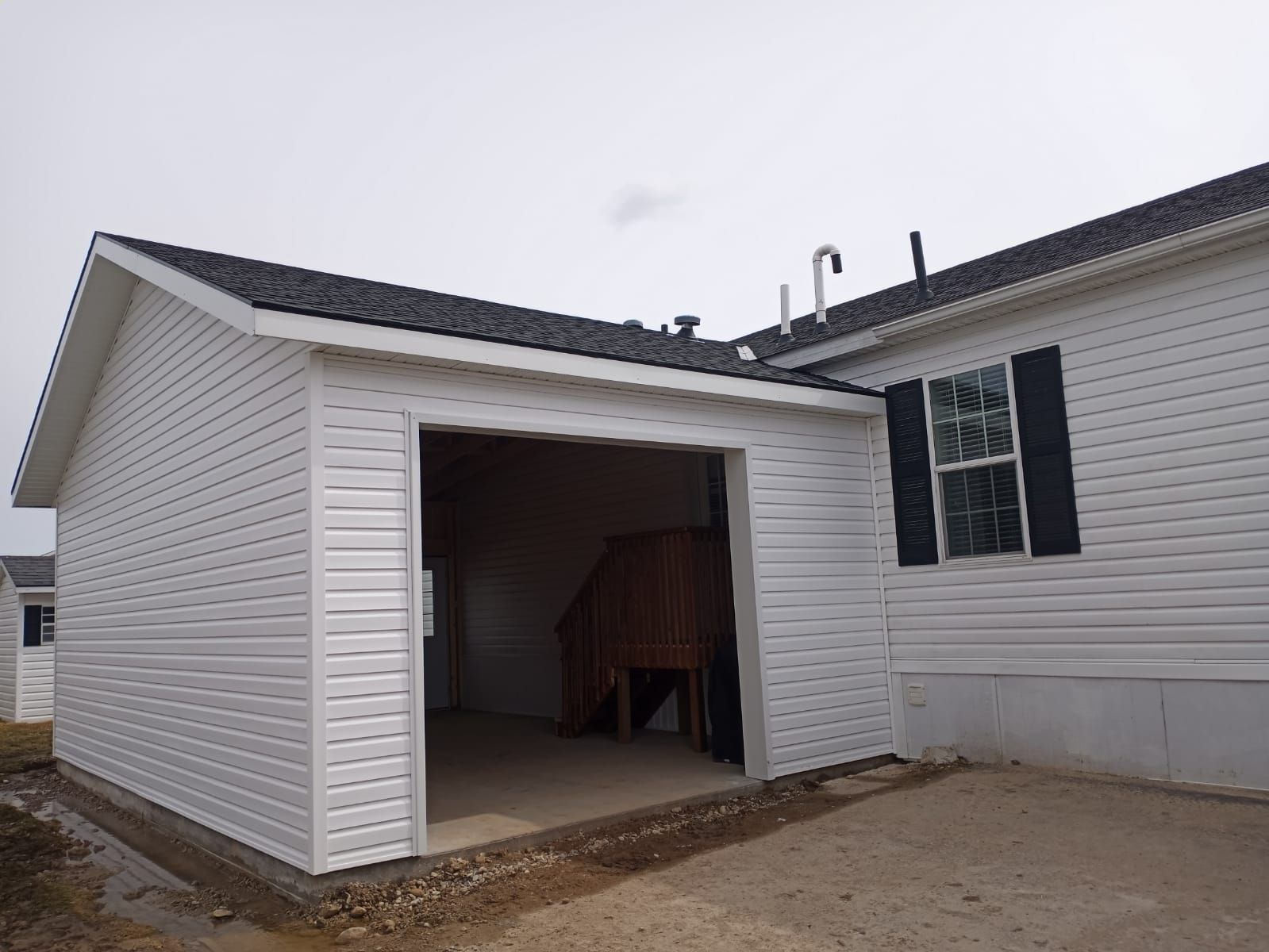 Open garage on a white house exterior with a concrete driveway and overcast sky.