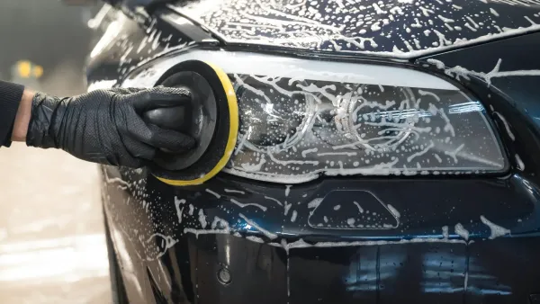 A person is polishing the headlight of a car.
