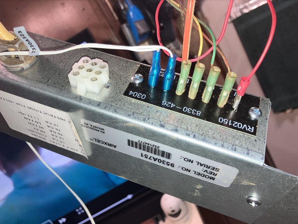 Close-up of a circuit board with colored wires, fuses, and a white connector inside a metal device