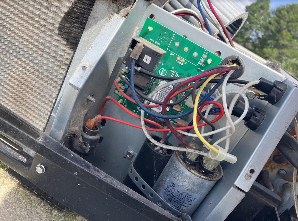 Open metal electrical box with circuit board and tangled colored wires inside