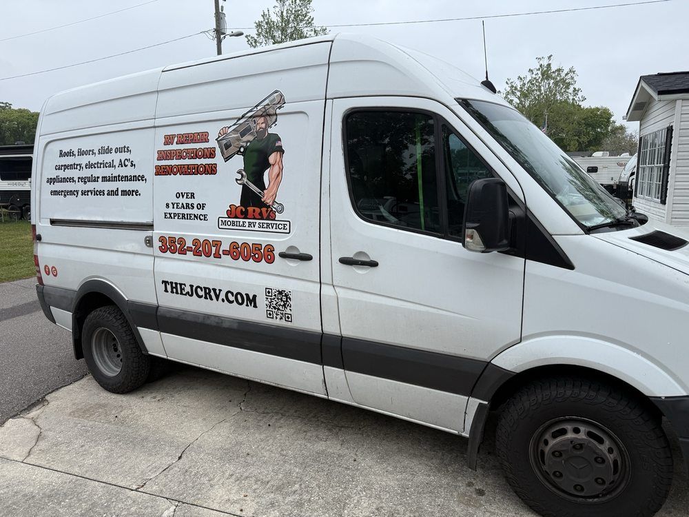 White plumbing service van with company logos and phone number parked on a street.