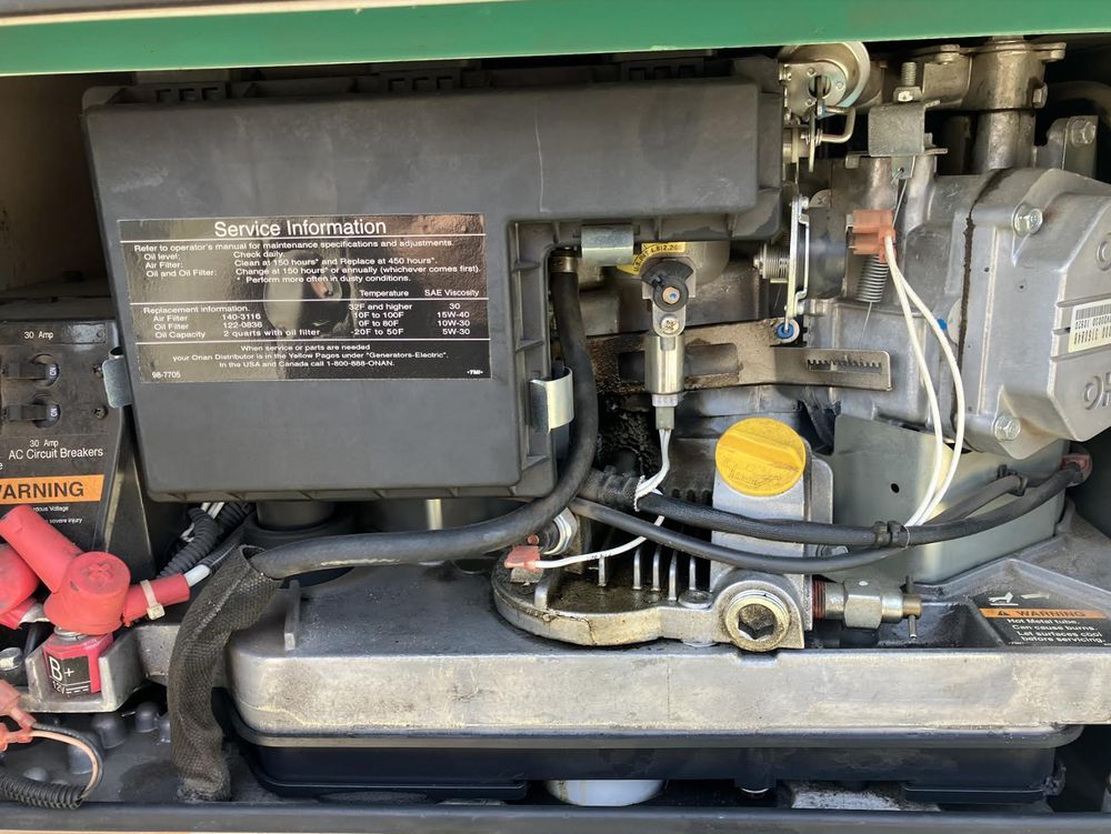 Close-up of a vehicle engine compartment with hoses, labels, and a yellow cap.