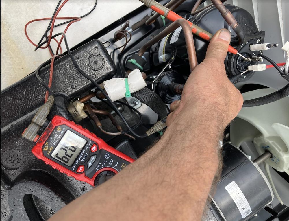 A person tests an air conditioner with a multimeter. The device displays 