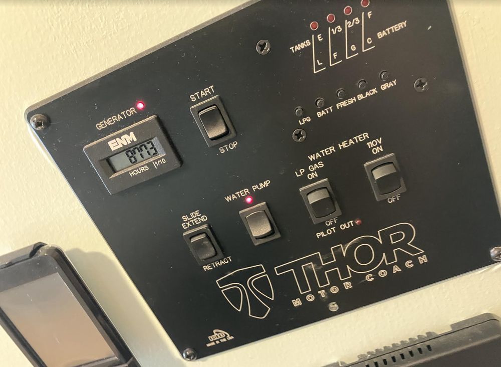 Close-up of a Thor wood stove control panel with switches and indicator lights, tilted against a beige background