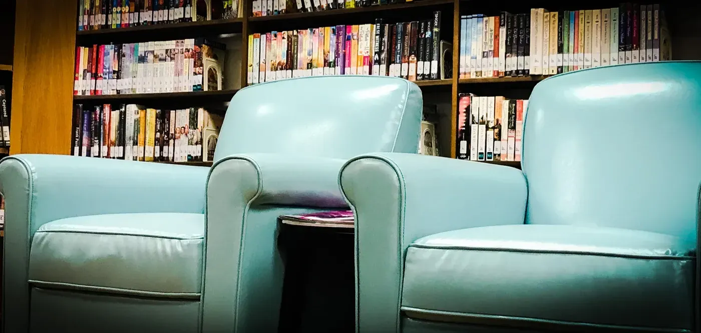 Two chairs are sitting in front of a bookshelf in a library.
