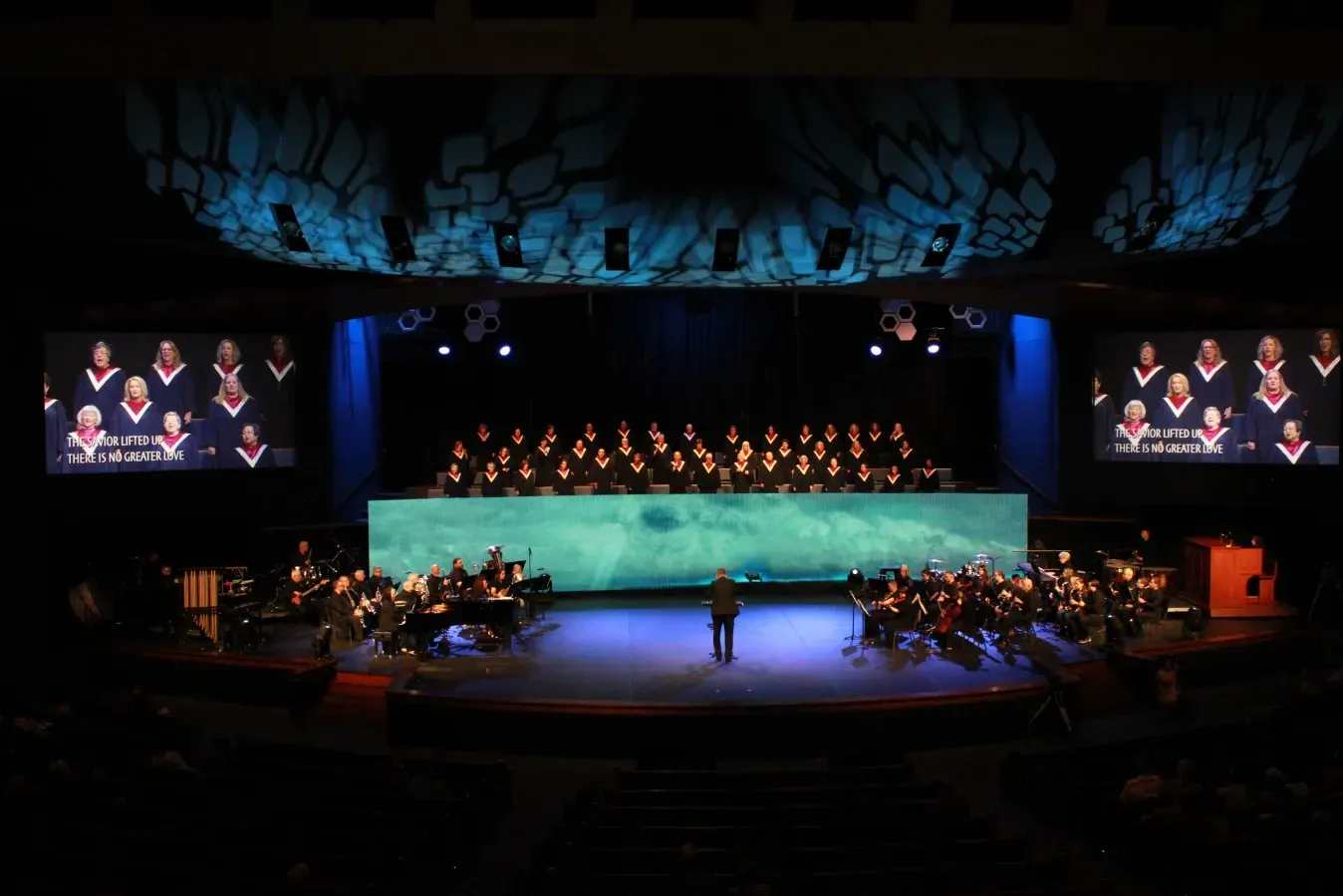 A large choir and orchestra are performing on a stage.