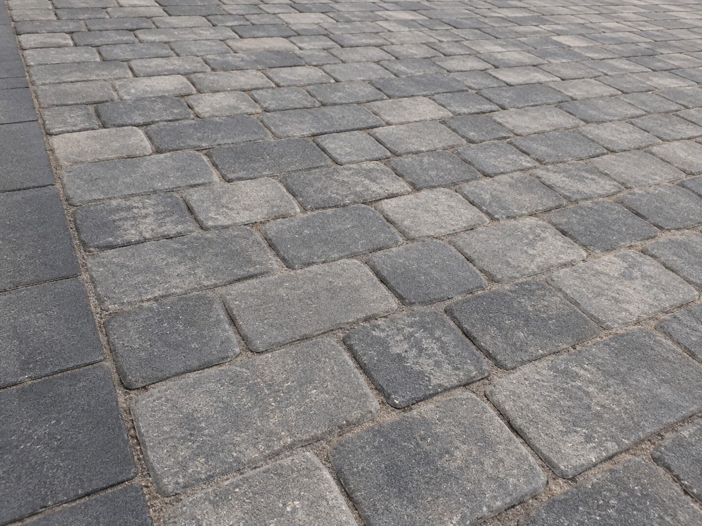 Grey cobble-effect concrete paving laid in staggered courses beside a charcoal border.