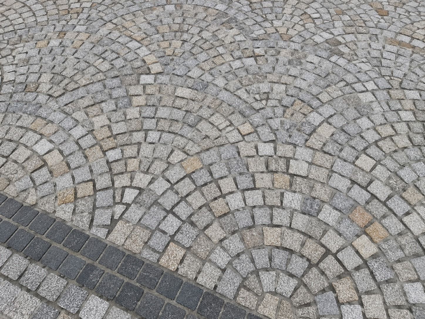 Grey granite setts arranged in a fan pattern with a contrasting charcoal stone border.