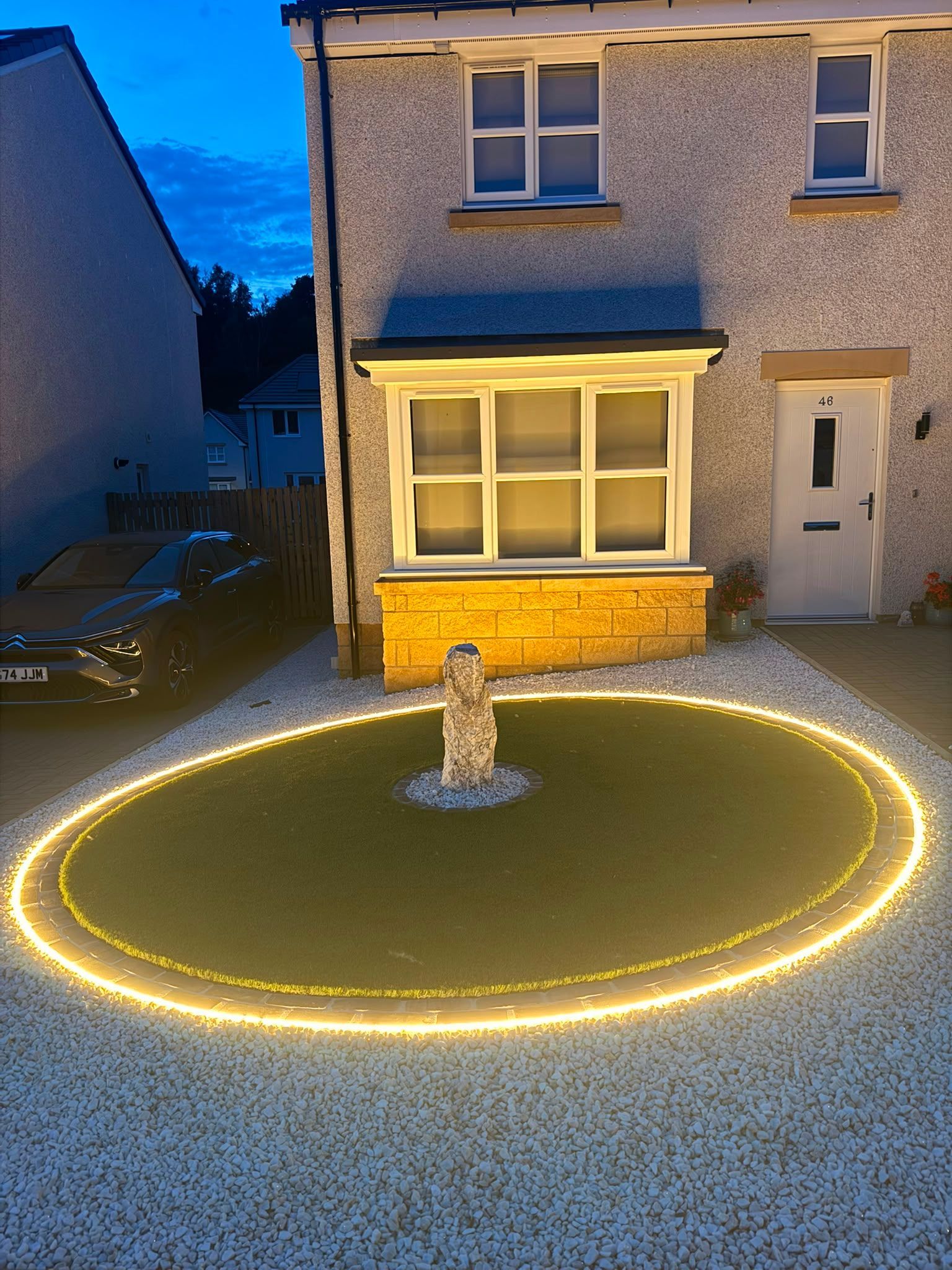 Completed circular front garden in Croy with artificial grass, feature rock and illuminated border