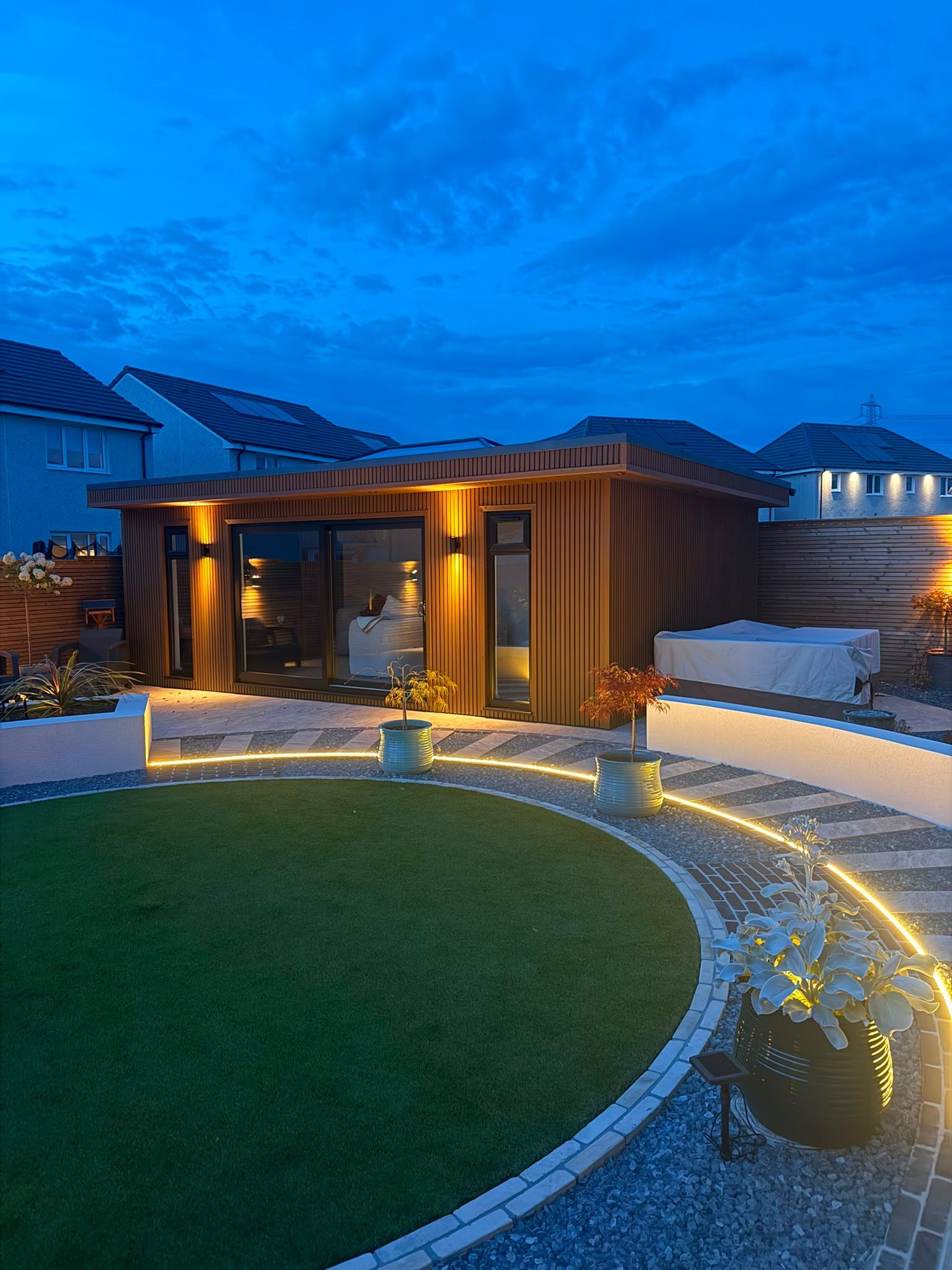 Completed rear garden transformation in Croy with a circular lawn, illuminated pathway and Oakspan garden room