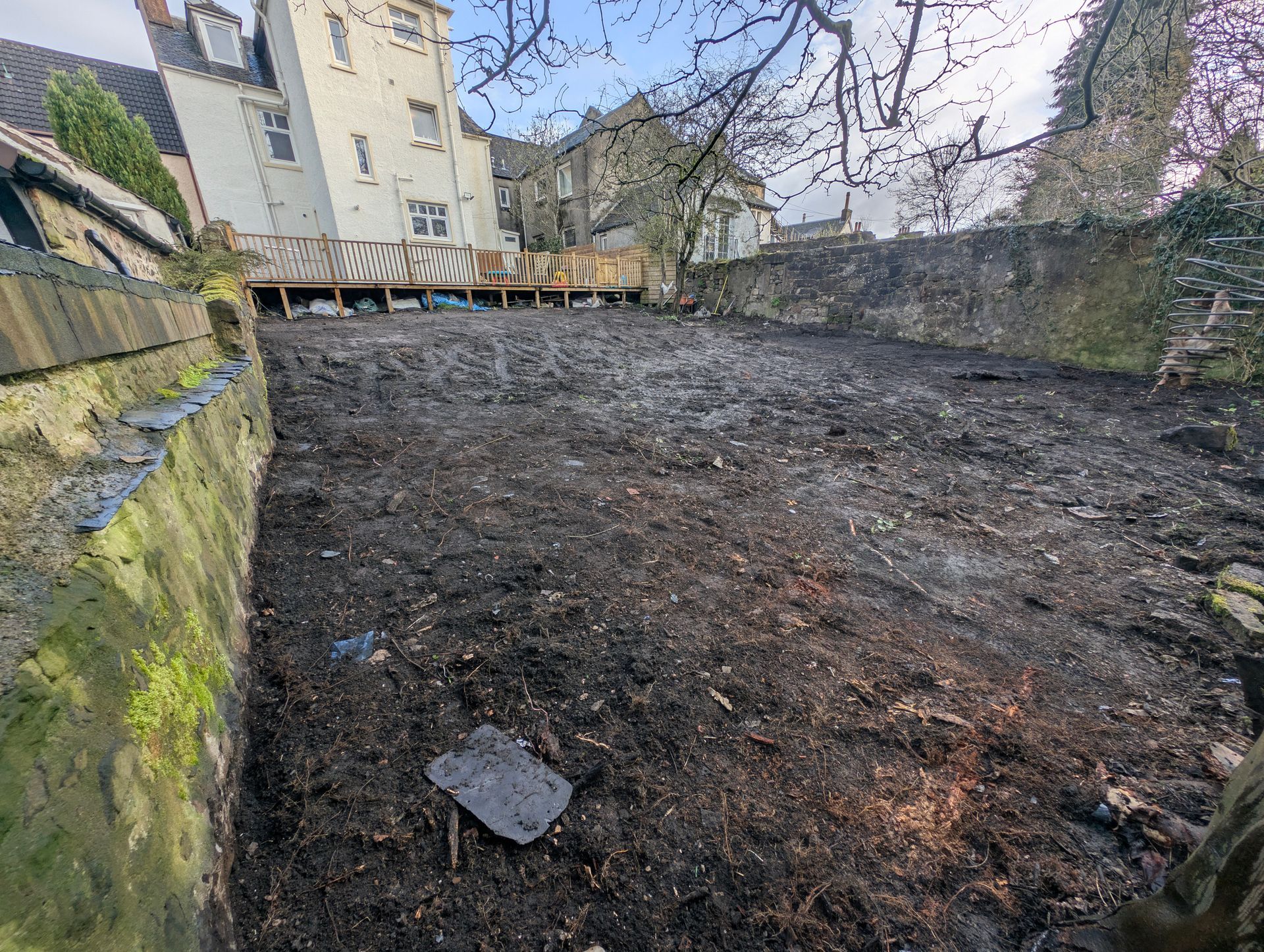 Before and after hard landscaping project in Glasgow showing an unprepared garden ground transformed into a finished lawn, patio and structured garden layout.
