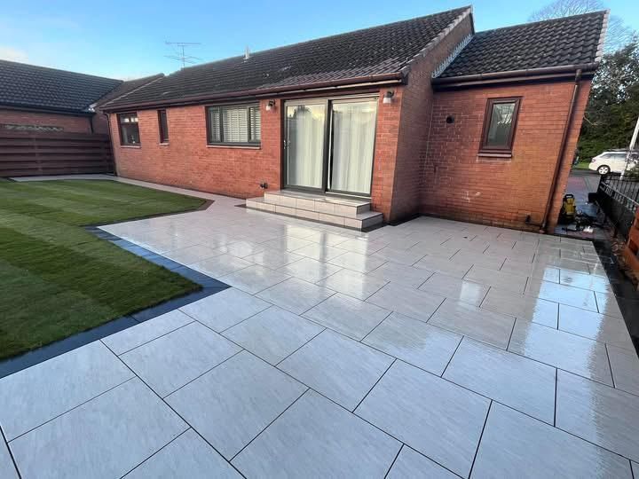 Completed porcelain patio in Glasgow with clean slab layout, lawn border and rear garden access.
