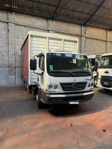 Camión Mercedes blanco estacionado dentro de la zona de carga de un almacén, vista frontal.