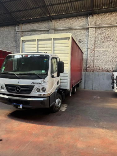 Camión Mercedes blanco estacionado dentro de la zona de carga de un almacén, vista frontal.