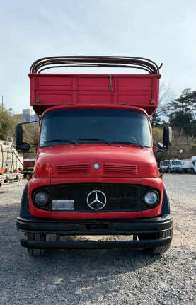 Camioneta Mercedes roja estacionada en un terreno de grava bajo un cielo despejado.